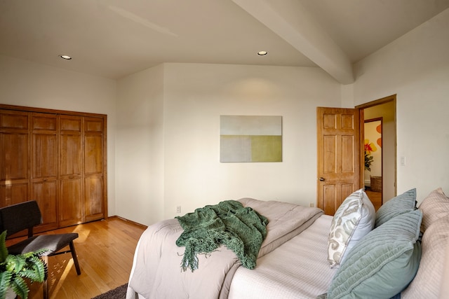 bedroom featuring beamed ceiling, light hardwood / wood-style floors, and a closet