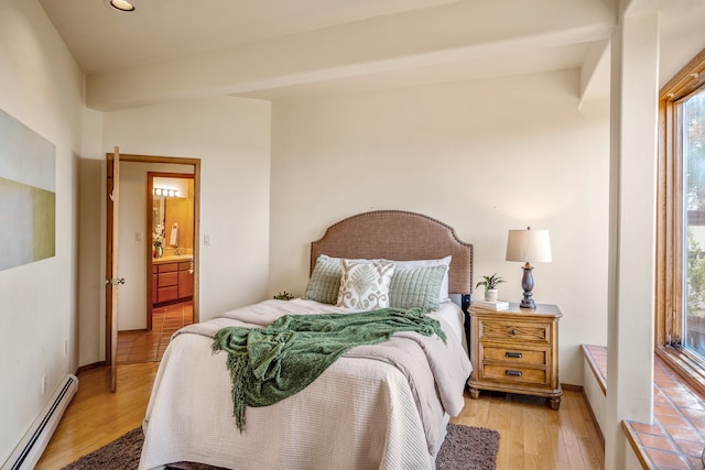 bedroom featuring baseboard heating, ensuite bath, and light wood-type flooring