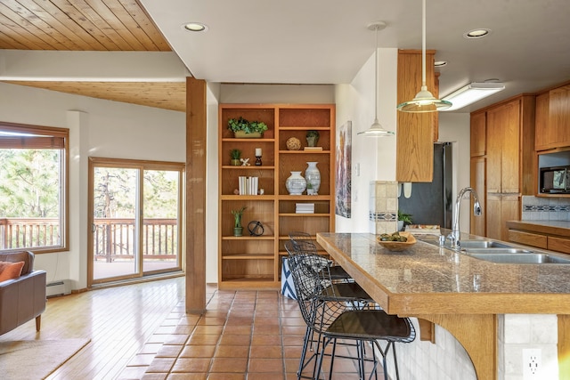 kitchen featuring stainless steel refrigerator, sink, a kitchen breakfast bar, dark hardwood / wood-style floors, and pendant lighting