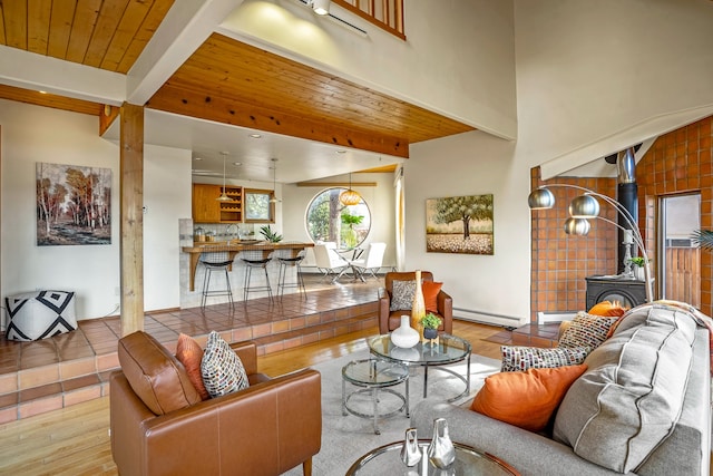 living room featuring a wood stove, wooden ceiling, light hardwood / wood-style floors, baseboard heating, and beam ceiling