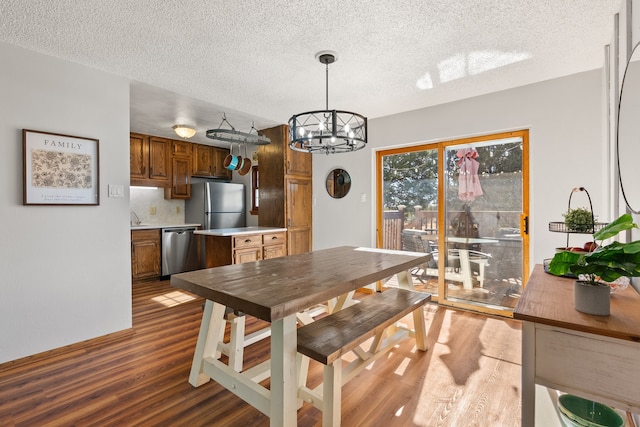 dining space with hardwood / wood-style floors, a textured ceiling, a notable chandelier, and sink