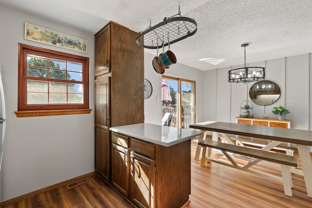 kitchen featuring wood-type flooring, a textured ceiling, a wealth of natural light, and a notable chandelier