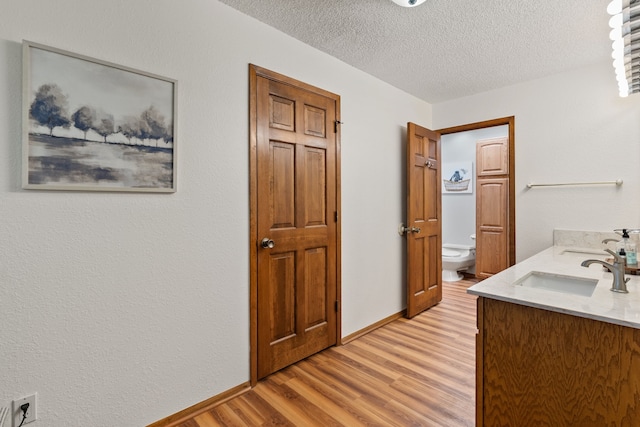 bathroom with hardwood / wood-style flooring, vanity, toilet, and a textured ceiling