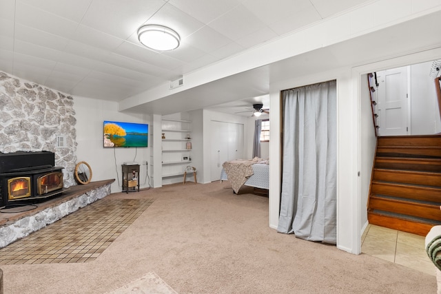 carpeted living room featuring ceiling fan and a wood stove