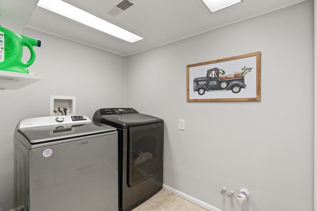 clothes washing area with independent washer and dryer and light tile patterned floors