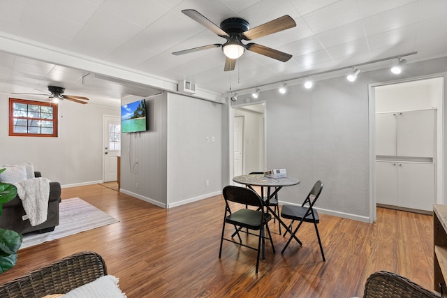 dining space featuring hardwood / wood-style floors, rail lighting, and ceiling fan