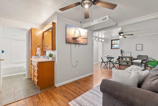 living room with light wood-type flooring, ornamental molding, and sink