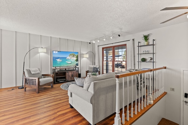 living room featuring ceiling fan, hardwood / wood-style floors, and a textured ceiling