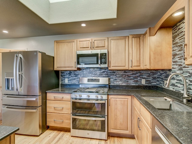 kitchen with sink, stainless steel appliances, light hardwood / wood-style floors, a textured ceiling, and decorative backsplash