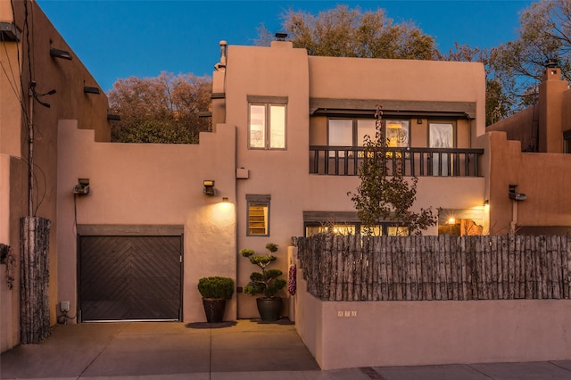 pueblo revival-style home with a balcony and a garage