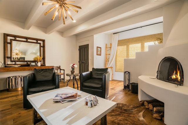 living room featuring beamed ceiling, a notable chandelier, a large fireplace, and light wood-type flooring