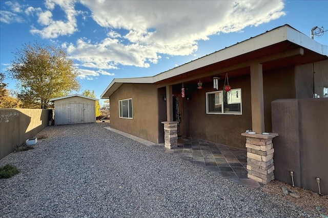 view of side of home with a patio and a storage shed