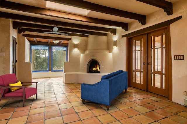 interior space with french doors, a large fireplace, ceiling fan, and beamed ceiling