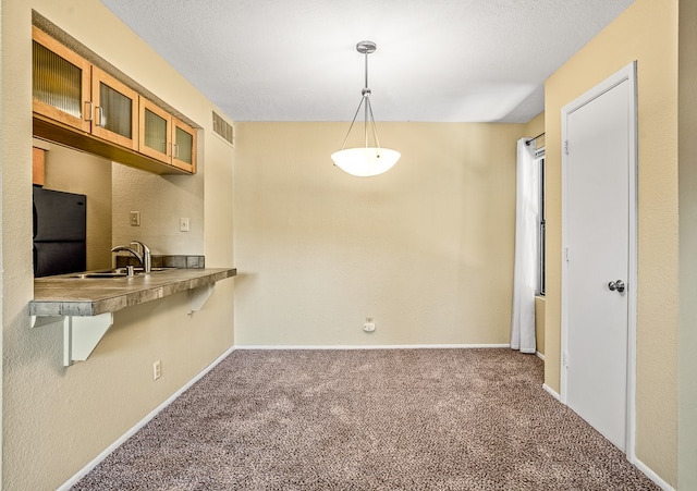 kitchen with black fridge, a breakfast bar, sink, decorative light fixtures, and carpet floors