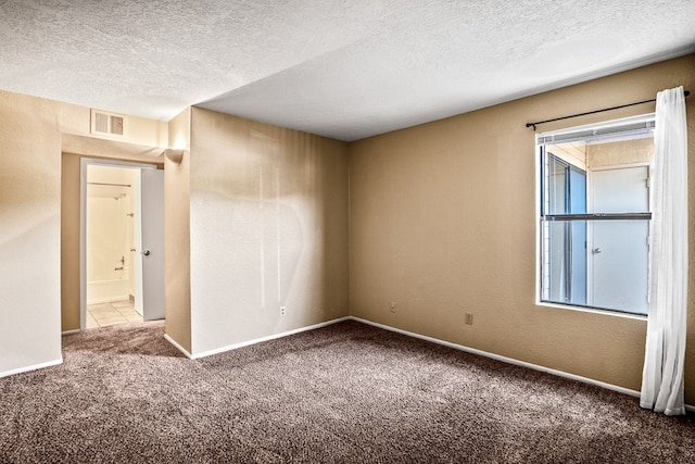 carpeted spare room featuring a textured ceiling and plenty of natural light