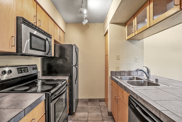 kitchen featuring track lighting, dark tile patterned flooring, sink, a textured ceiling, and appliances with stainless steel finishes