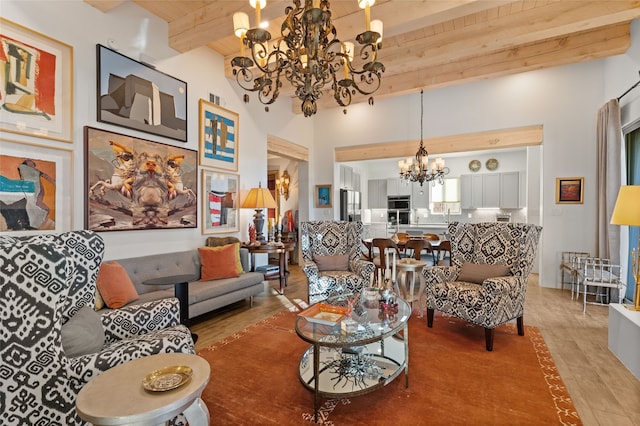 living room with a high ceiling, light wood-type flooring, beam ceiling, wood ceiling, and a chandelier