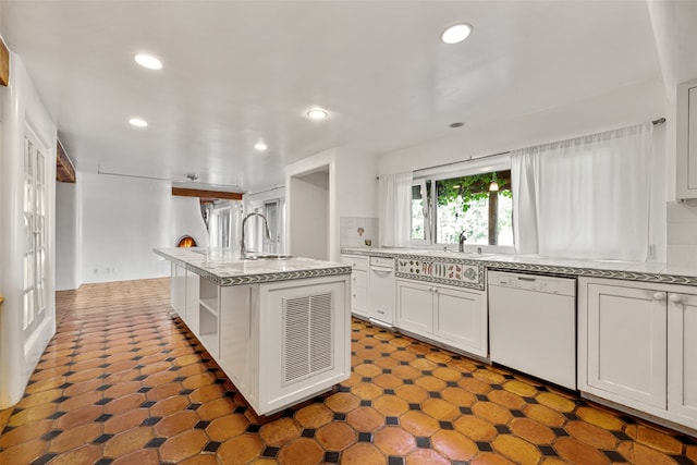 kitchen featuring dishwasher, white cabinets, a center island with sink, and sink