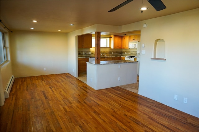 kitchen featuring decorative backsplash, white appliances, a baseboard radiator, dark stone countertops, and light hardwood / wood-style floors