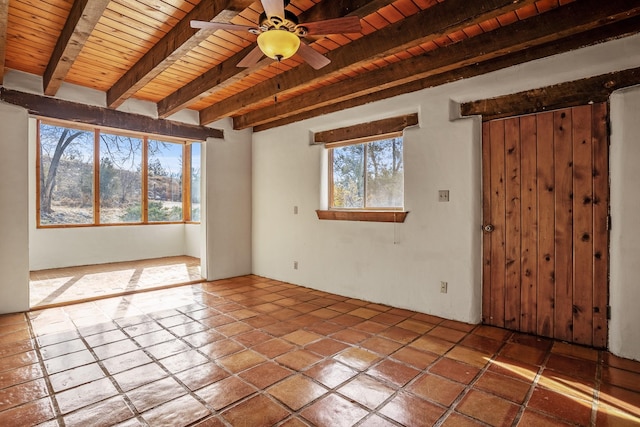 tiled spare room featuring beamed ceiling, ceiling fan, and wood ceiling