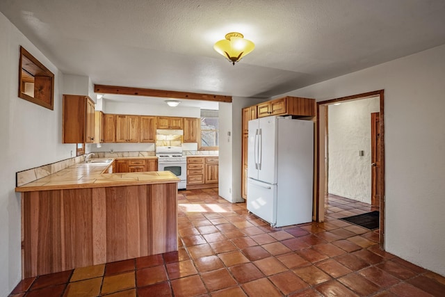 kitchen featuring kitchen peninsula, a textured ceiling, white appliances, sink, and beamed ceiling