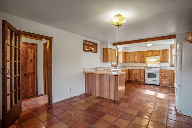 kitchen featuring kitchen peninsula, beam ceiling, white appliances, and a textured ceiling