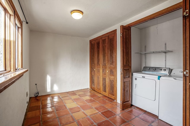 washroom featuring washer and clothes dryer, light tile patterned flooring, and a textured ceiling