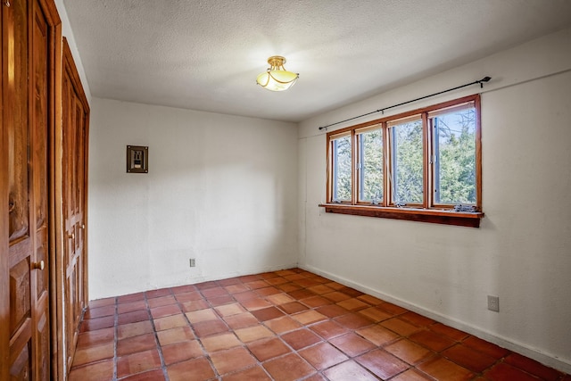 tiled empty room featuring a textured ceiling