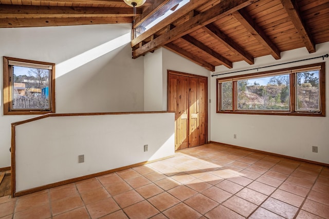 tiled empty room featuring vaulted ceiling with beams and wooden ceiling