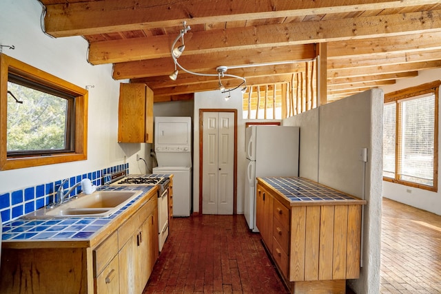 kitchen featuring white appliances, tile counters, a wealth of natural light, and stacked washer / drying machine