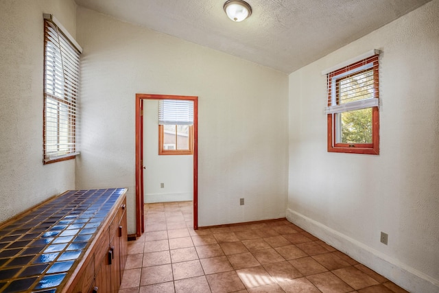 interior space with tile patterned flooring, a textured ceiling, and a wealth of natural light