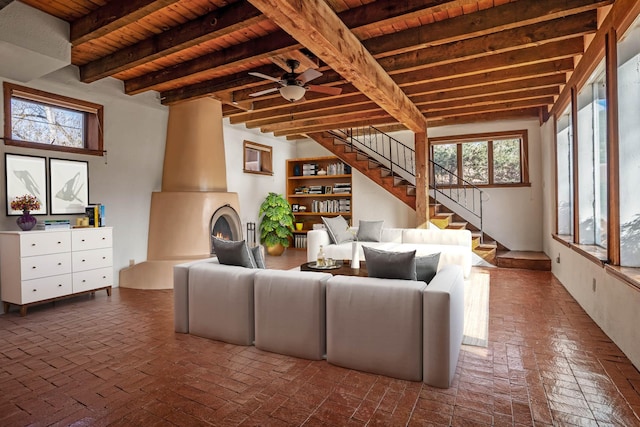 unfurnished living room featuring beamed ceiling, a wealth of natural light, wooden ceiling, and ceiling fan