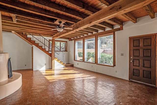 unfurnished living room featuring beam ceiling, ceiling fan, and wood ceiling