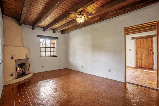 unfurnished living room featuring beamed ceiling, ceiling fan, wood ceiling, and a fireplace