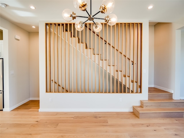 stairs featuring wood-type flooring and a notable chandelier