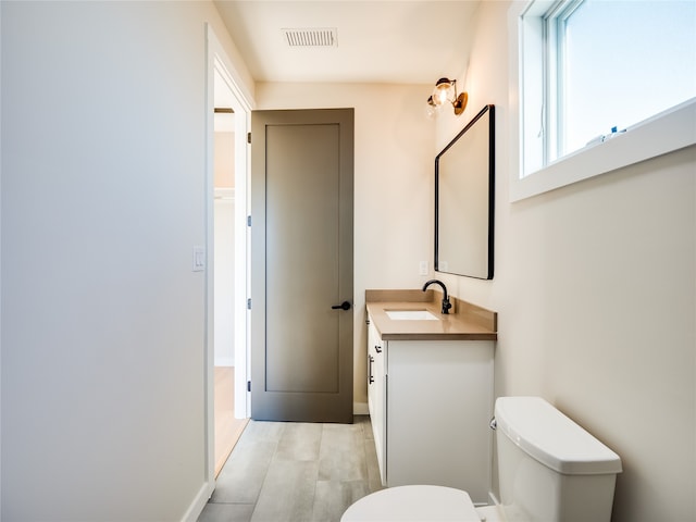 bathroom featuring vanity, wood-type flooring, and toilet