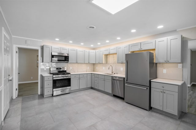 kitchen featuring gray cabinetry, decorative backsplash, sink, and appliances with stainless steel finishes