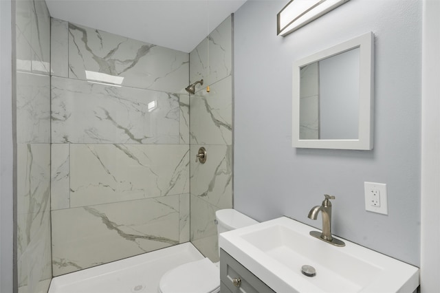 bathroom with vanity, toilet, and tiled shower