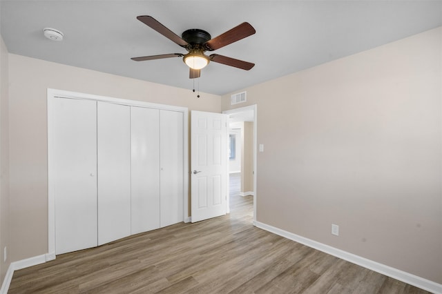 unfurnished bedroom with ceiling fan, light hardwood / wood-style floors, and a closet