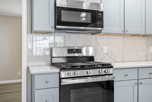 kitchen with backsplash, hardwood / wood-style floors, and appliances with stainless steel finishes