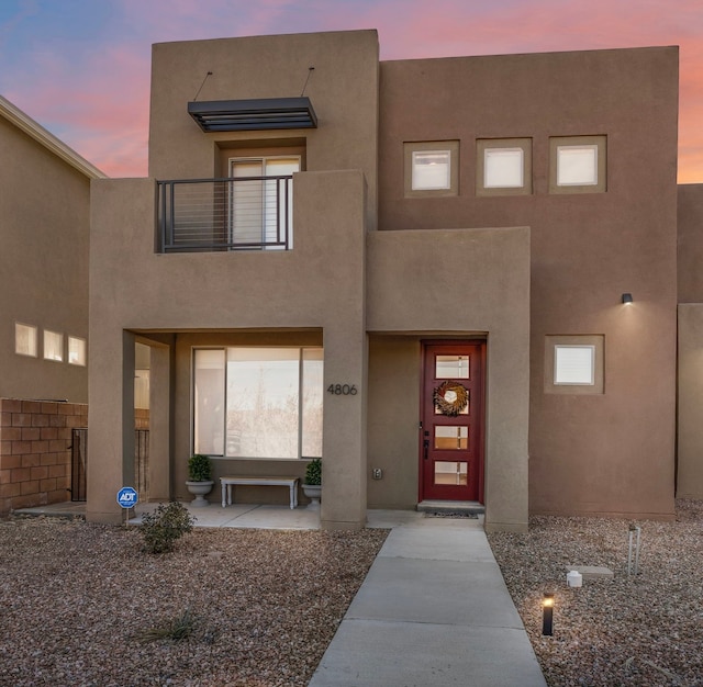 entrance to property with a balcony and stucco siding