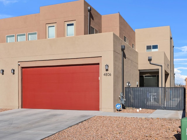 adobe home with concrete driveway, an attached garage, and stucco siding