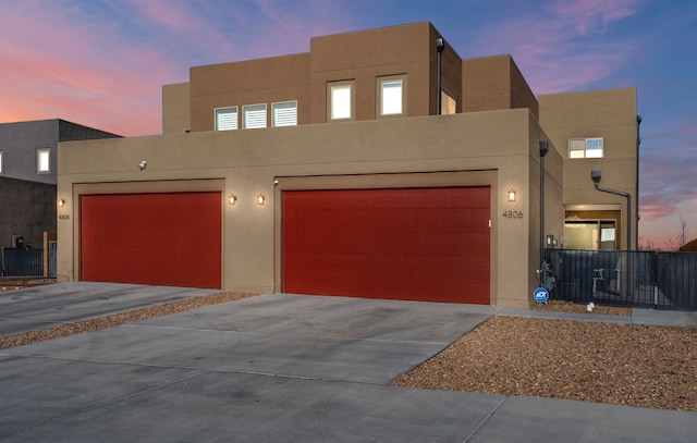 view of front of house featuring stucco siding, concrete driveway, and fence