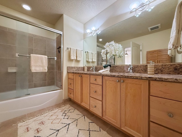 bathroom featuring tile patterned flooring, vanity, enclosed tub / shower combo, and a textured ceiling