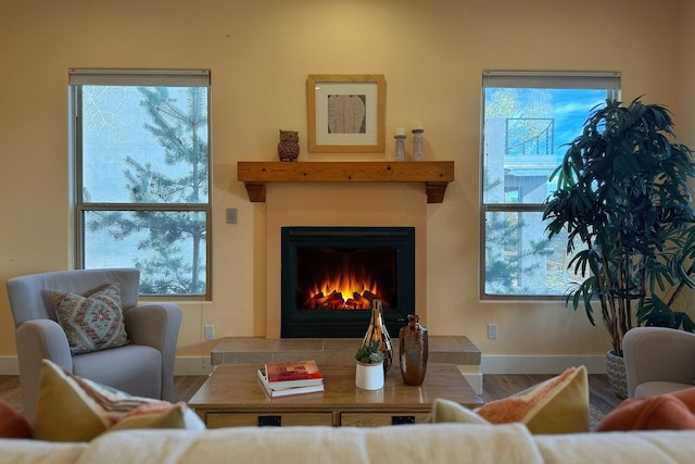 living room featuring wood-type flooring, a wealth of natural light, and a tiled fireplace