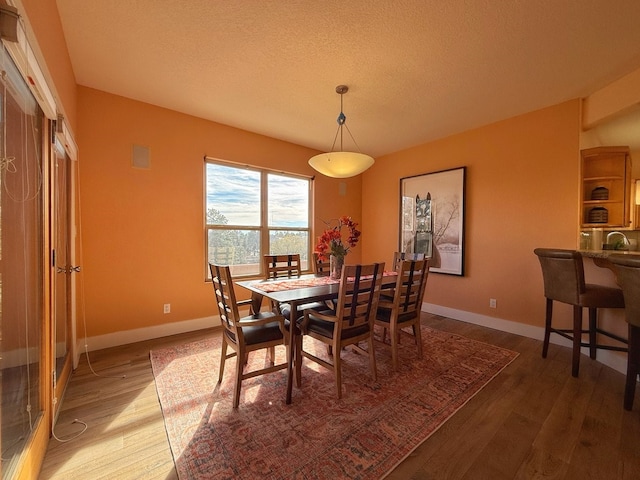 dining room with a textured ceiling, hardwood / wood-style flooring, and sink