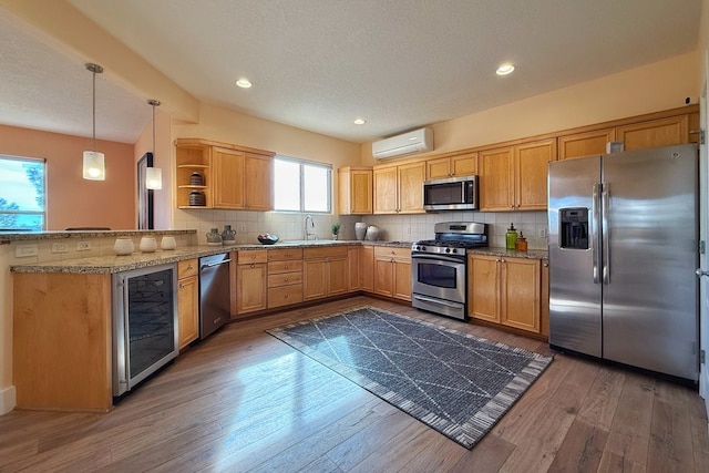 kitchen with an AC wall unit, kitchen peninsula, a wealth of natural light, and stainless steel appliances