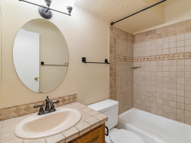 full bathroom featuring vanity, a textured ceiling, toilet, and tiled shower / bath