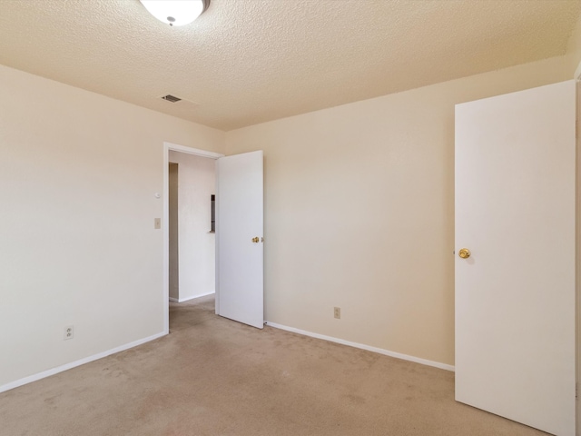 unfurnished room featuring a textured ceiling and light colored carpet