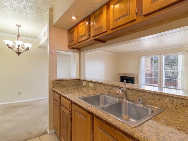 2501 Zia Rd Unit 10-210, Santa Fe, NM 87505 - kitchen featuring crown molding, brown cabinetry, light colored carpet, a tiled fireplace, and a sink